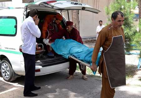 Afghan medical workers carry one of the bodies of two foreign women who were gunned down by men on a motorcycle, at the morgue of Herat hospital on July 24, 2014. Two foreign female aid workers were shot dead by unknown gunmen while travelling in a taxi in the western Afghan city of Herat, officials said. Photo AFP- LEHTIKUVA.