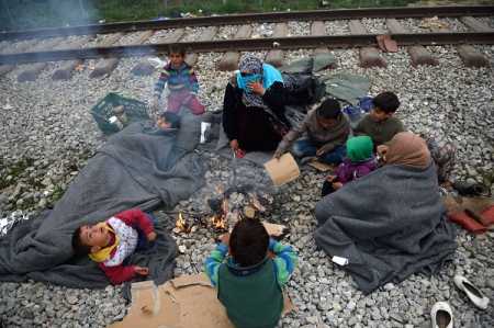 Migrants get warm by a fire on March 18, 2016 at a makeshift camp at the Greek-Macedonian border, near the Greek village of Idomeni. Tens of thousands of refugees are trapped in dire conditions after Balkan countries shut their borders, many of them at the overwhelmed border town of Idomeni. Photo AFP-LEHTIKUVA